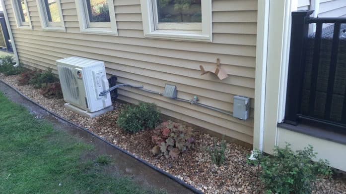 Client-supplied photograph of an exterior heat pump on a wall bracket