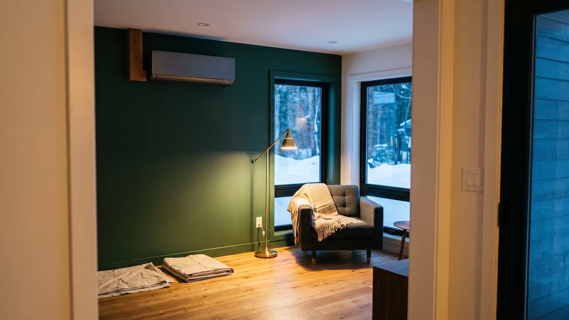 Living room with a wall-mounted indoor heat pump head and snow outside the windows