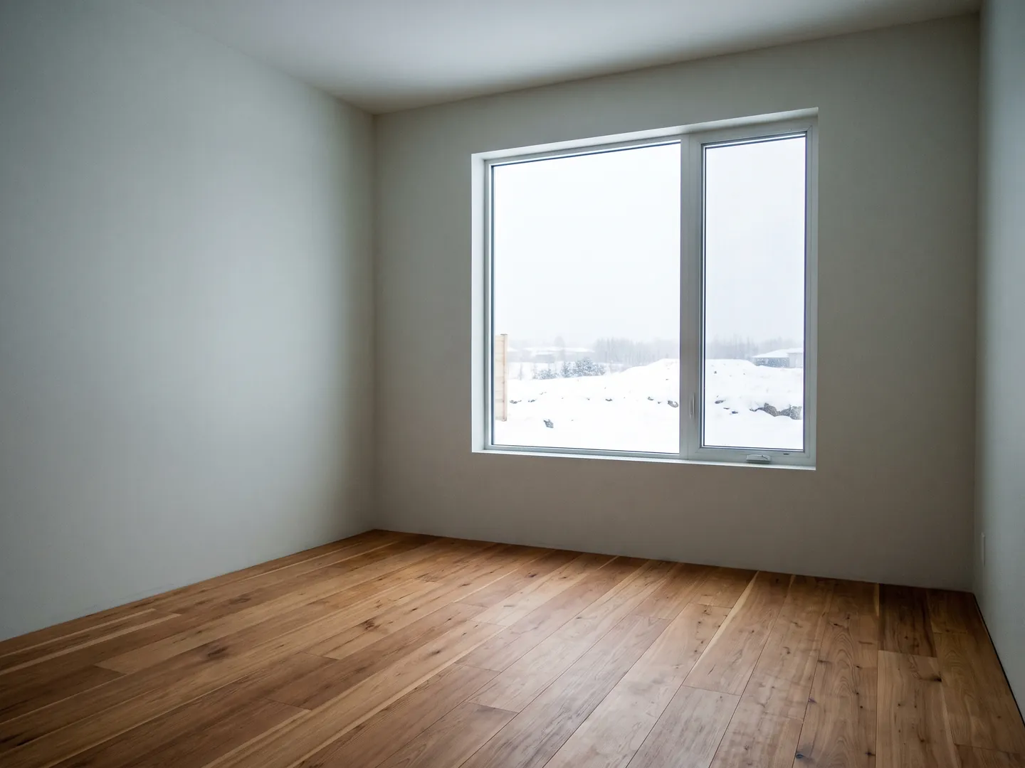 Empty unfurnished room with bare walls and a window looking onto snow
